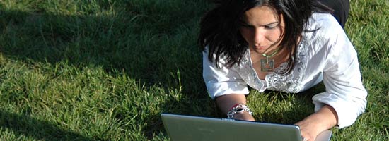 Frau mit Laptop auf Wiese