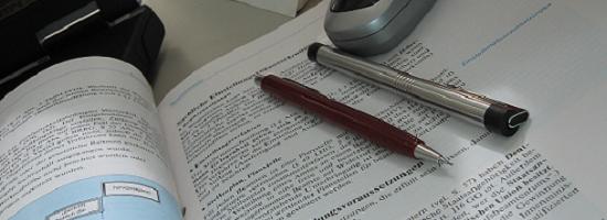Aufgeschlagenes Lehrbuch mit Stiften